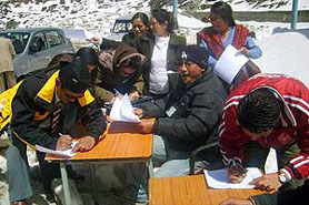 Traders from the Indian side fill forms for their fresh travel passes on the Indo-China border at Nathu La pass in the presence of industry department officials on the first day of the reopening of the border after eight months.