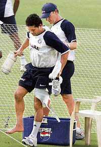 Sachin Tendulkar is assisted by team physio John Gloster as he limps out of the ground during a training session in Kolkata on Wednesday.
