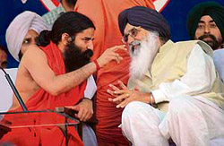 Yoga guru Swami Ramdev makes a point to Chief Minister Parkash Singh Badal in Patiala on Thursday. 