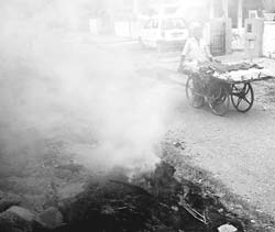 Smoke from burning leaves swirls around on the roadside in Karnal