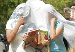 Two girls cover themselves with a dupatta to keep the harsh sun at bay in Ludhiana