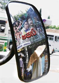 An advertisement of a local film is reflected off the rear-view mirror of a vehicle in Colombo on Sunday. Sri Lanka announced slapping a new tax of nearly $2,500 on every local production, which employs foreign actors, in a move seen as discouraging cheaper artistes from neighbouring India which has the worlds largest film industry.