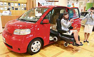An employee of Toyota Motors demonstrates the company's mii-van Porte, which can load an electric wheelchair into the driver's seat automatically, in Tokyo.