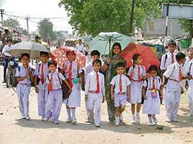 Schoolchildren take shelter under umbrellas to escape heat while returning home in Ludhiana on Wednesday