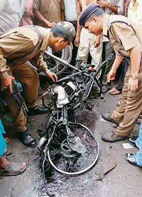 Policemen inspect a damaged motorbike at a bomb blast site in Guwahati.