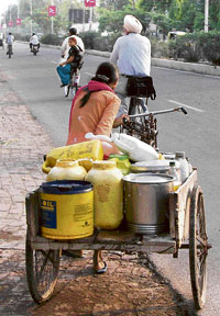 A woman carries containers filled with water in Ambala on Tuesday. With summer at its peak, there is an acute shortage of water in the city.