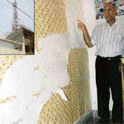 Dr Madan Lal Kaushal of Mohali points towards a crack developed in the wall of his house due to the installation of a mobile tower (inset) on the top of a neighbouring building