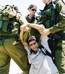 Israeli soldiers arrest an international activist during a protest against Israel's controversial separation barrier in the West Bank village of Umm Salamona, near Bethlehem