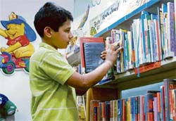BOOK-ED: A young boy riffles through a bookshelf for summer reading.