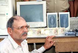 Rajender with seized counterfeit currency worth Rs 2.5 lakh and a computer at Karnal 