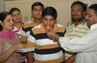 Taranjit being offered sweets after he secured the fourth position in the class VIII examination, while his elder twin Manjit stood third.