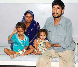Mohan Thakur, a poor man who is paralysed, with his wife and children who are suffering from broncho pneumonia and measles due to malnutrition and infection.
