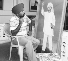 Inderjeet Singh Chitarkar with a portrait of Shaheed Bhagat Singh that he has made.