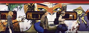 Commuters walk past a Pendolino train at a London station. The train has been designed by British designer Jamie Hewlett to promote his latest opera Monkey: Journey to the West at the ongoing Manchester International Festival.