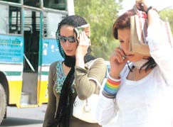 Girls try to protect themselves from heat wave blowing during the day in the Capital