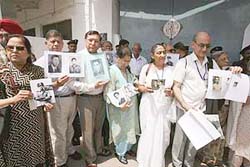 Indian nationals hold pictures of their missing relatives outside a jail in Lahore