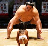 A girl lines up against a professional sumo wrestler before the start of the second day of the Grand Sumo Tournament in Hawaii