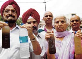 Residents show bottles filled with dirty water that is being supplied in their locality in Mohali