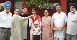 Director of Shri Guru Harkrishan Public School, Doraha, Umal Kaur, offers sweets to Hardeep Kaur, a student of school, who stood third in Class X exams held by the Punjab School Education Board.