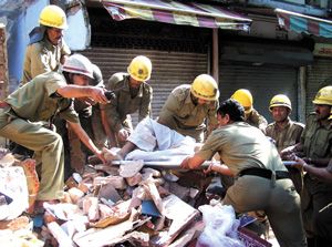Fire brigade personnel rescue an injured person from the debris of two-storeyed shopping complex which collapsed in the Gulabi Bagh area in the Capital on Monday. 