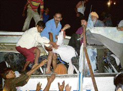 An injured bus passenger being rescued by people.
