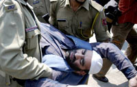 Policemen carry Mirwaiz-led Hurriyat leader Zaffar Iqbal,who was assaulted by Shiv Sena activists during a press conference, at the Jammu Press Club in Jammu on Sunday.