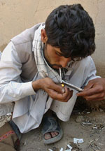 An Afghan man sits in a garbage-strewn yard smoking heroin in Kabul on Tuesday as International Day against Drug Abuse and Illicit Trafficking is observed worldwide.