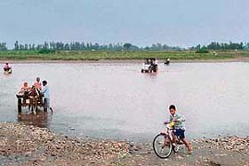 Residents of villages located on the Indo-Pak border across the Ujj river carry foodgrains and other essential commodities to tide over the rainy season