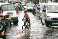 A kid enjoys rain as he cycles through a waterlogged road in Ludhiana on Thursday.
