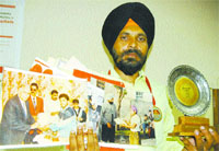 The weightlifter shows medals and trophies won by him.