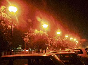 With moisture levels high owing to the rain, an illuminated city road gives the impression of a foggy evening in the summer in Ludhiana.