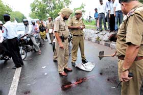 Delhi Police officials inspect the spot on a Delhi-Noida road where a shootout took place in the Capital