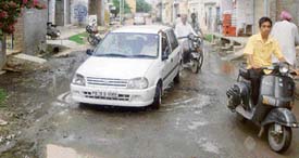 A driver tries to steer clear of potholes at the Jagera Road at Ahmedgarh