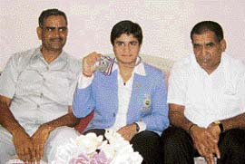 Geetika Jakhar flanked by her coach, Ram Avatar (left), and father, Satbir Jakhar, shows the silver medal she won at the Commonwealth Wrestling Championship.