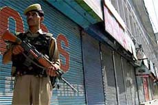 A jawan stands guard in front of shops during a strike call given by the Hurriyat Conference in Srinagar on Friday.