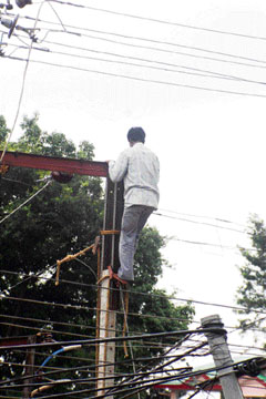 A lineman mends transmission lines on an electricity pole without any safety belt, helmet and shoes near the post office, Dharamsala, on Thursday.