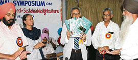 Dr M.S. Kang, flanked by PAU officials, releases a souvenir during a symposium on disease-free seeds at PAU in Ludhiana