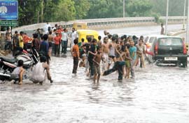 Children enjoy a heavy downpour in the Capital
