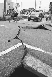 A man passes a crack on a road in Kashiwazaki. A powerful 6.8-magnitude earthquake rocked Japan on Monday, killing five persons and injuring hundreds as it toppled houses and sparked a fire at one of the worlds biggest nuclear plants.