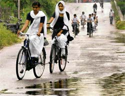 Schoolchildren negotiate a puddle on their bicycles as they are caught in a drizzle in Chandigarh on Monday.