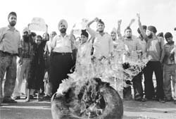 Sikhs burn a tyre in protest against WWF wrestler Booker -T, who had worn trunks with a Sikh religious symbol in a bout, in Jammu on Wednesday
