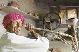 Farmer Pratap Singh smokes a hukka pipe in his home in Neemana, some 100 km from New Delhi. Pratap was the owner of a 20-acre (eight-hectare) fertile field that yielded three harvests a year until his sons persuaded him to sell.