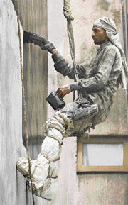 Anand Mandal a migrant construction worker lays a coat of waterproofing compund to the outer wall of a house.