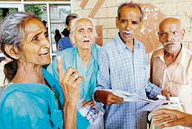 Usha Rani (left) and Lachman Dass (right), along with their neighbours, show documents of the house at the mini-secretariat.