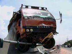 A mini truck hangs on the railing of a flyover near Effco Chowk at national highway No 8 in Gurgaon on Monday