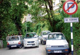 Cars parked under a no parking sign block traffic