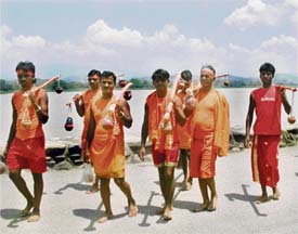 Flow of Faith: Kanwariyas walk along the Sukhna Lake after offering Ganga water at the Shiv Mandir in Saketri, on Monday.