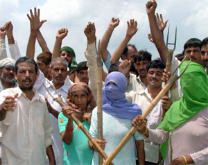Villagers oppose fencing of the farmland bought by a construction company at Gadoli village in Gurgaon on Monday.