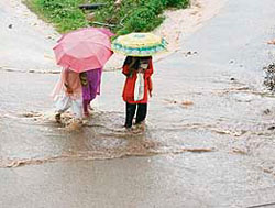 These college girls negotiate a water-logged road following a downpour on Wednesday, which disrupted life in Dharamsala.