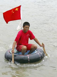 A man sits on his raft, made up of an automobile inner tube and a plastic basin, as he nears the bank of the Huangpu river in Shanghai on Monday.